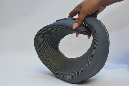 A hand holding a dark gray, U-shaped textured clutch bag against a plain white studio background.