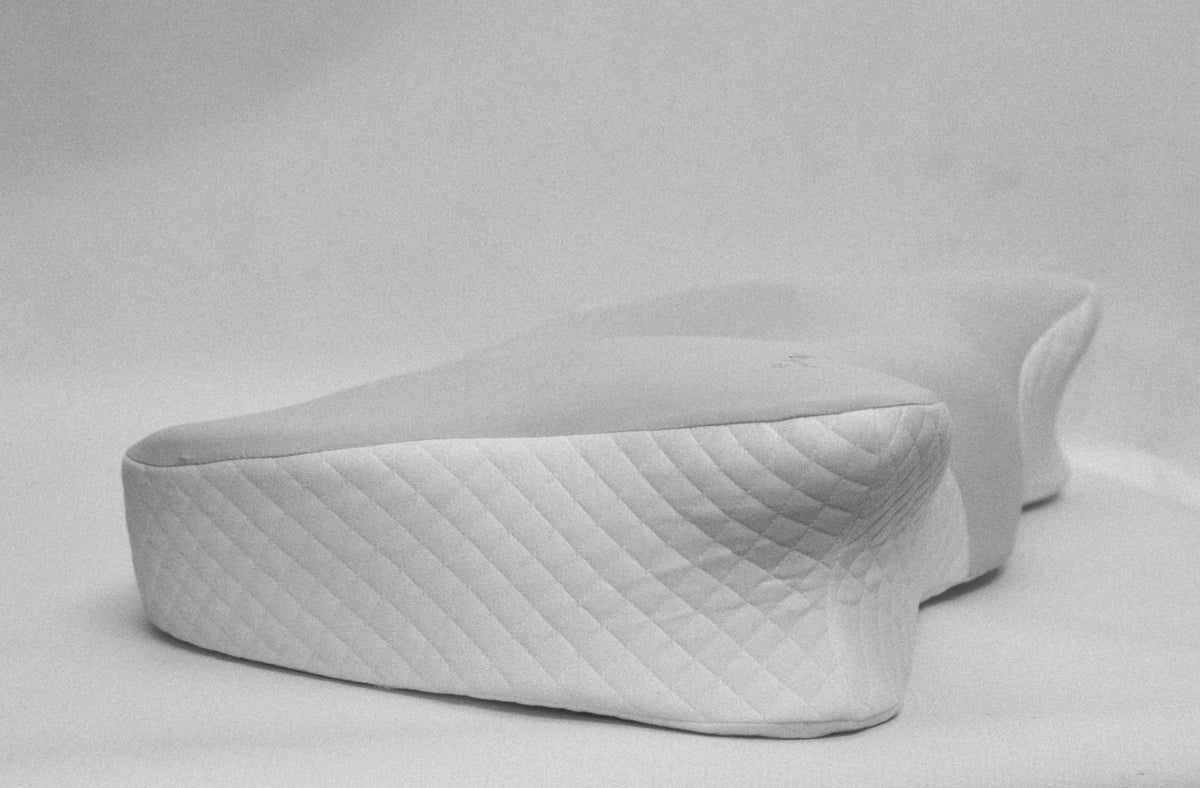 A white contoured pillow with a diamond-quilted side panel, shown on a light gray background.