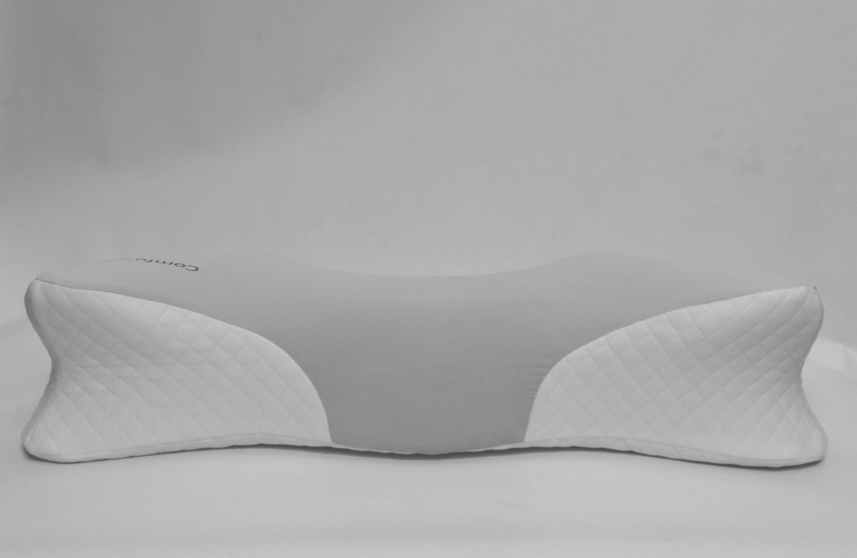 A white ergonomic neck pillow with quilted side panels and a smooth curved center, shown on a neutral light gray background.