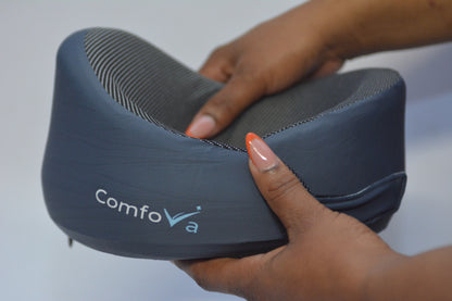 A person's hands holding a ComfoVa lumbar support pillow, showing its contoured shape and textured fabric.