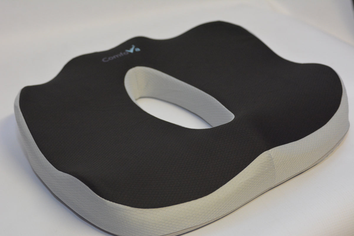 A black and white contoured seat cushion with a central cutout, featuring the brand name 'ComfortN' printed in white on the top surface.